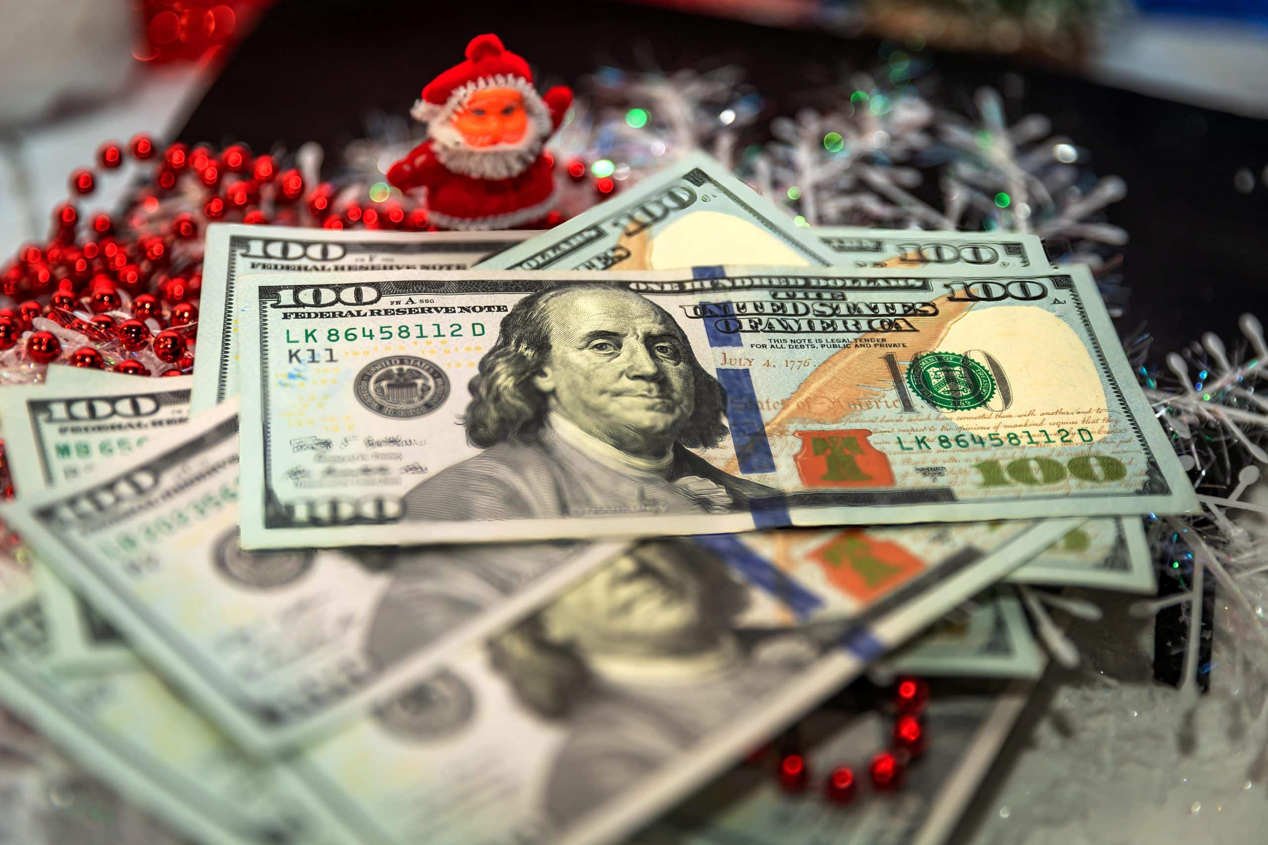 Stack of hundred dollar bills with festive red beads and holiday decorations