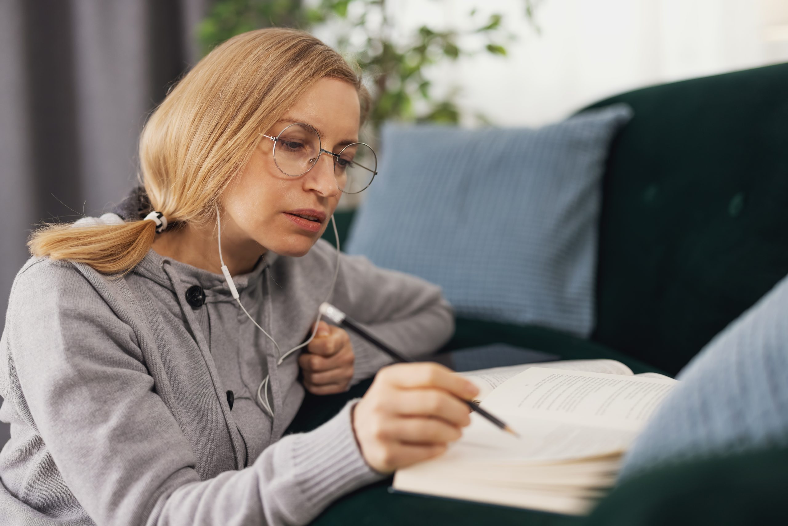 a woman sitting on a couch reading a book and studying