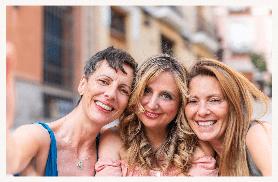 photo of 3 friend smiling as they take a selfie in the city. Canva download with border. 