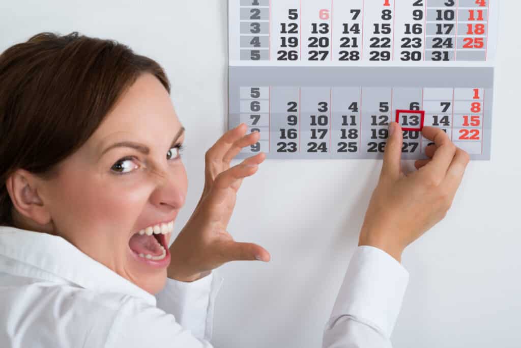 close up of scared business woman marking Friday  13th on calendar